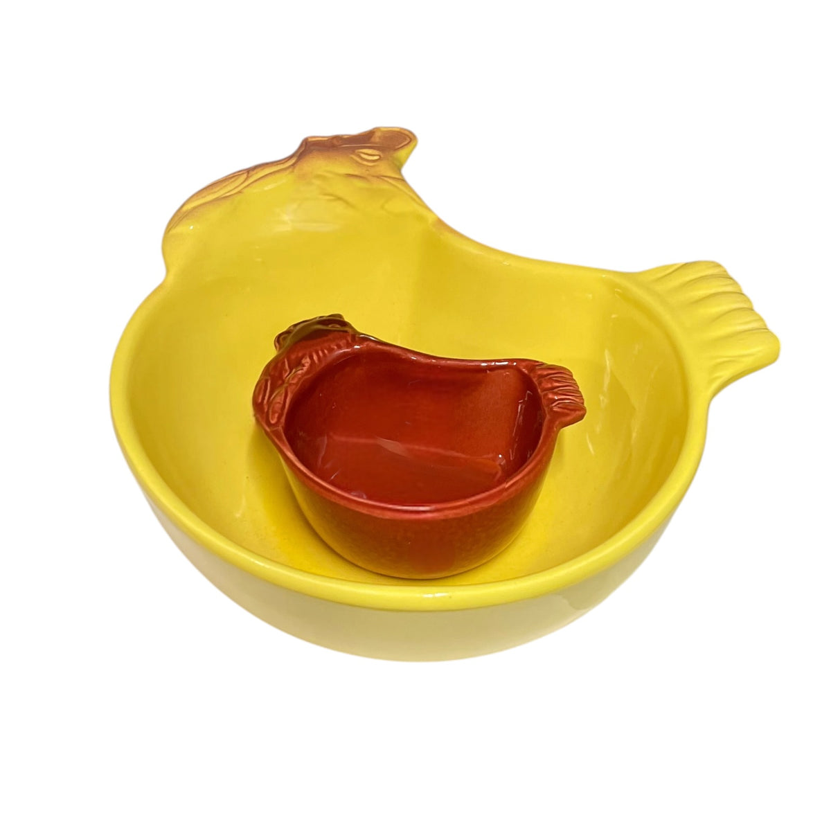 A yellow ceramic chicken-shaped bowl containing a smaller reddish-brown ceramic dish, set against a plain white background.