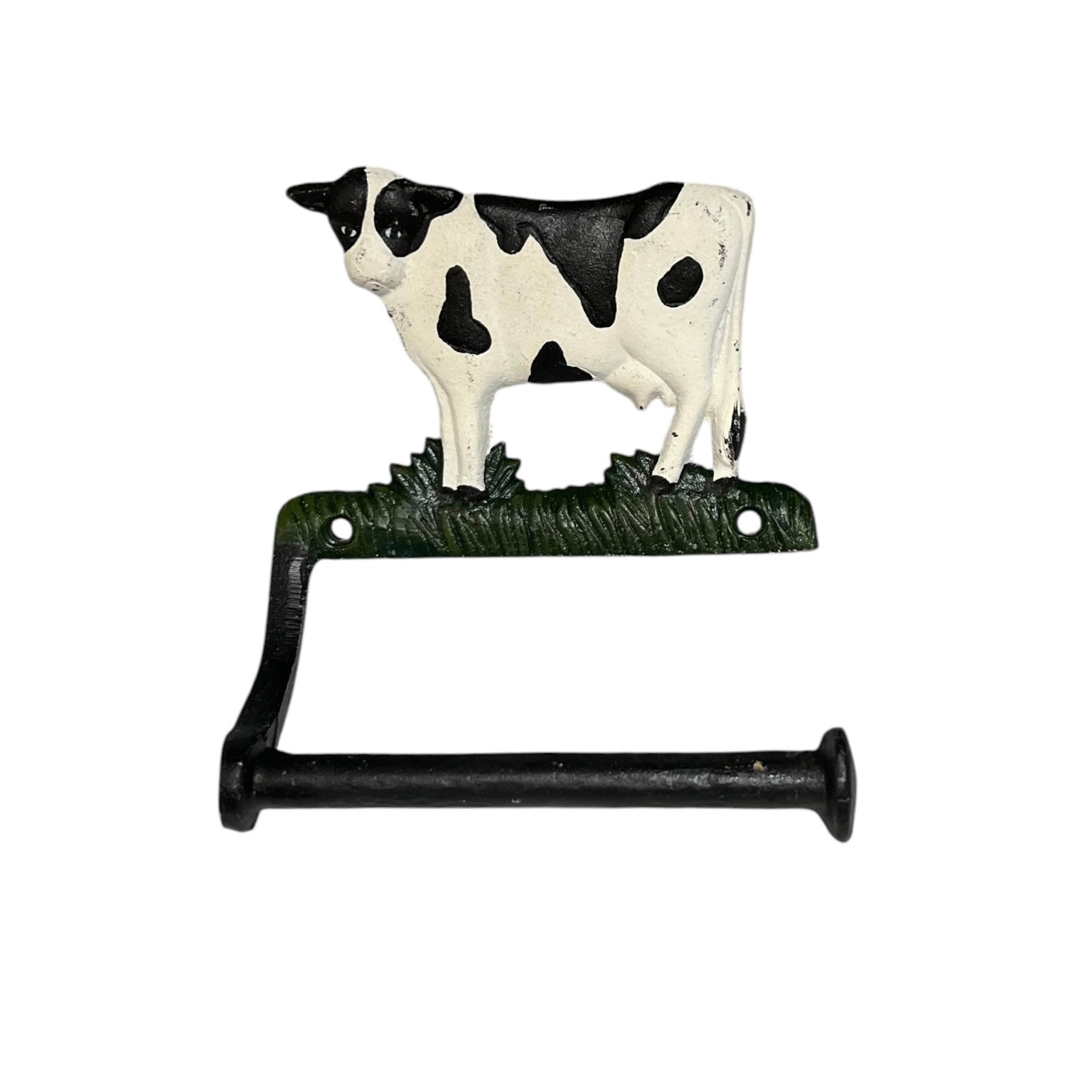 A decorative cast iron toilet paper holder featuring a black and white cow standing on a patch of green grass, mounted on a black L-shaped bracket.