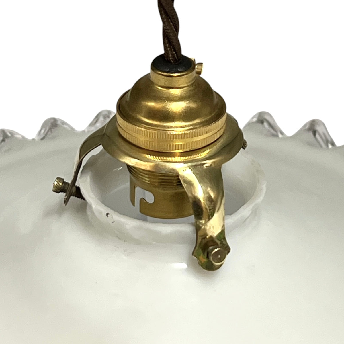 Close-up of a vintage white glass pendant light shade with a brass socket and hanging cord, shown against a white background.