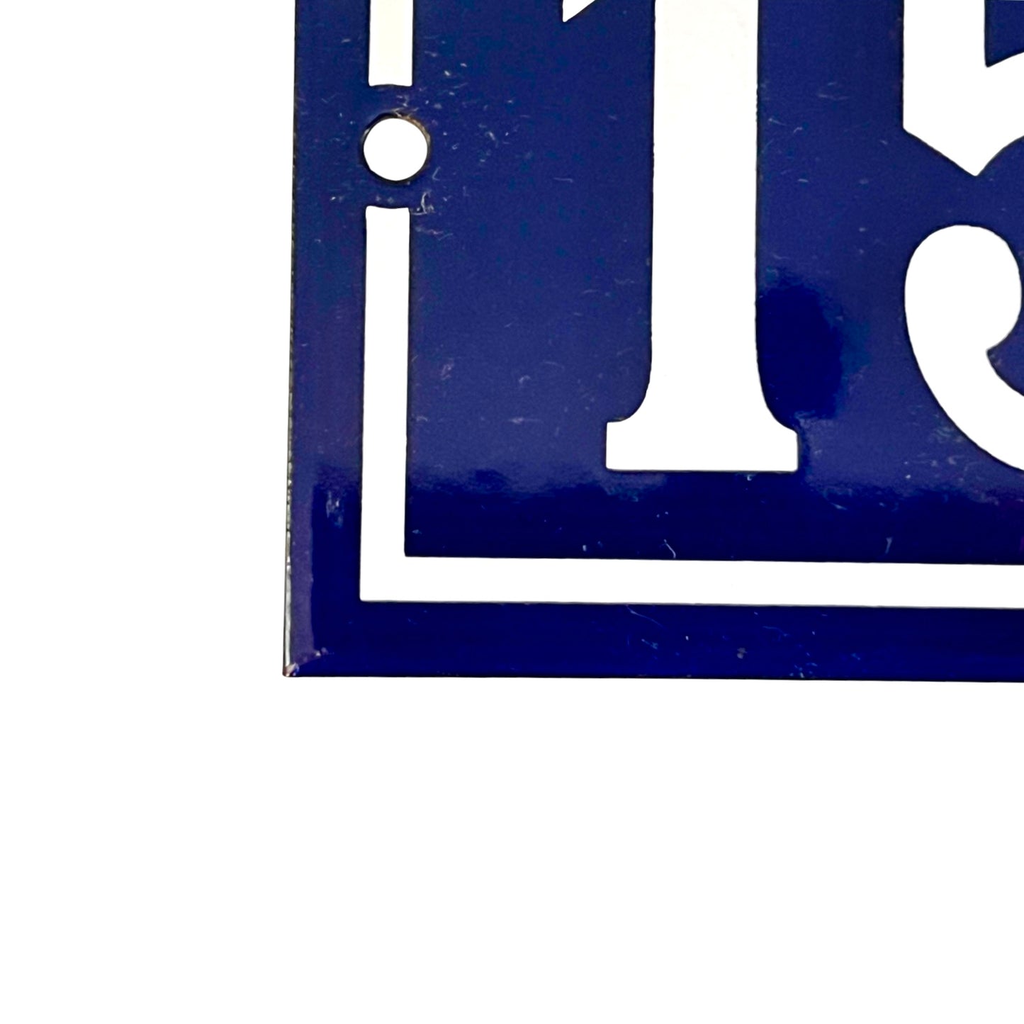 Close-up of a dark blue house number sign with white lettering and a small mounting hole, shown against a white background.