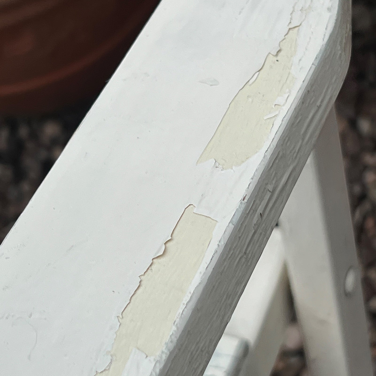 A close-up view of a painted wooden slatted garden chair set amidst a lush garden backdrop.