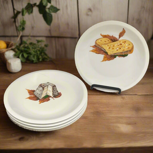 Set of white plates with cheese-themed designs on a wooden surface for sale from All Things French Store.