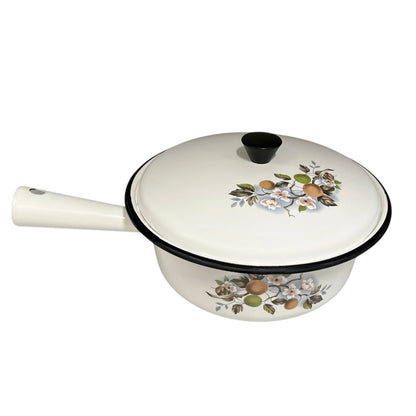 White enamel saucepan and lid with floral design on a white background