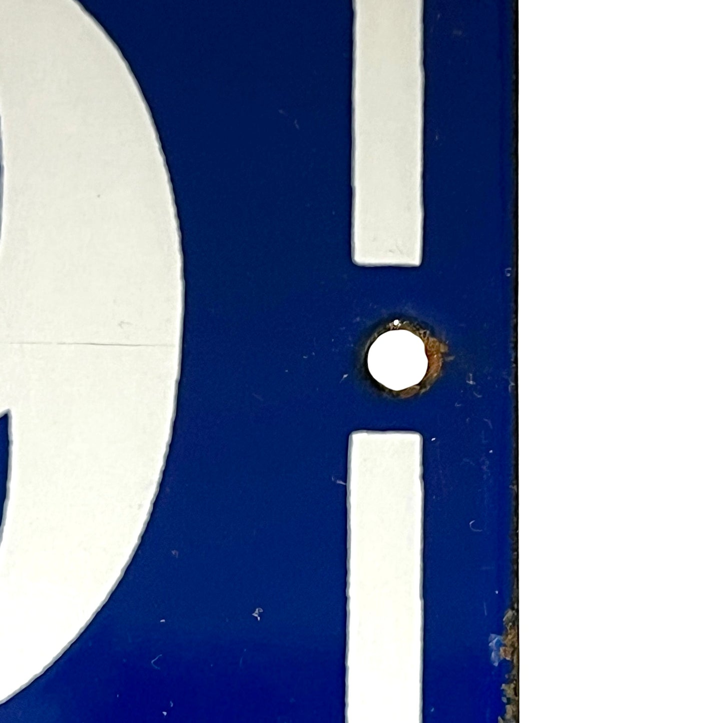 Close-up of a blue and white sign or panel with a small circular hole near the center.