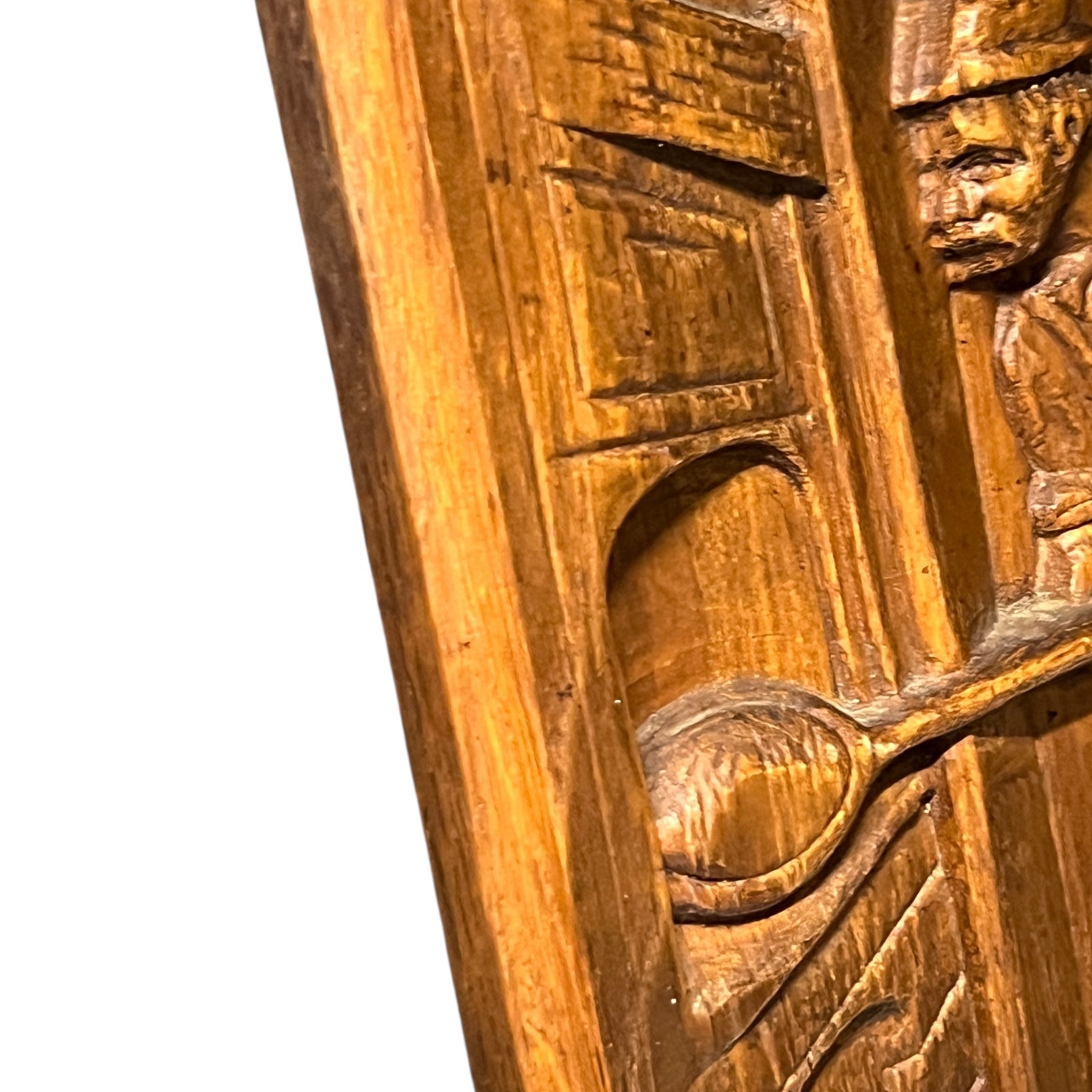 Wooden plaque with a carved design of a person holding a spoon.