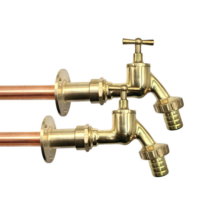 Two brass garden hose spouts with cross handles and threaded hose ends, shown with copper pipes on a plain white background.