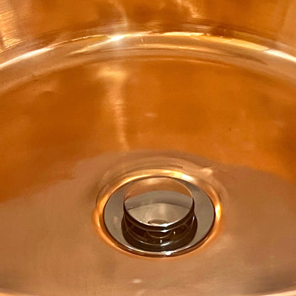 Close-up of a copper sink with a brass drain