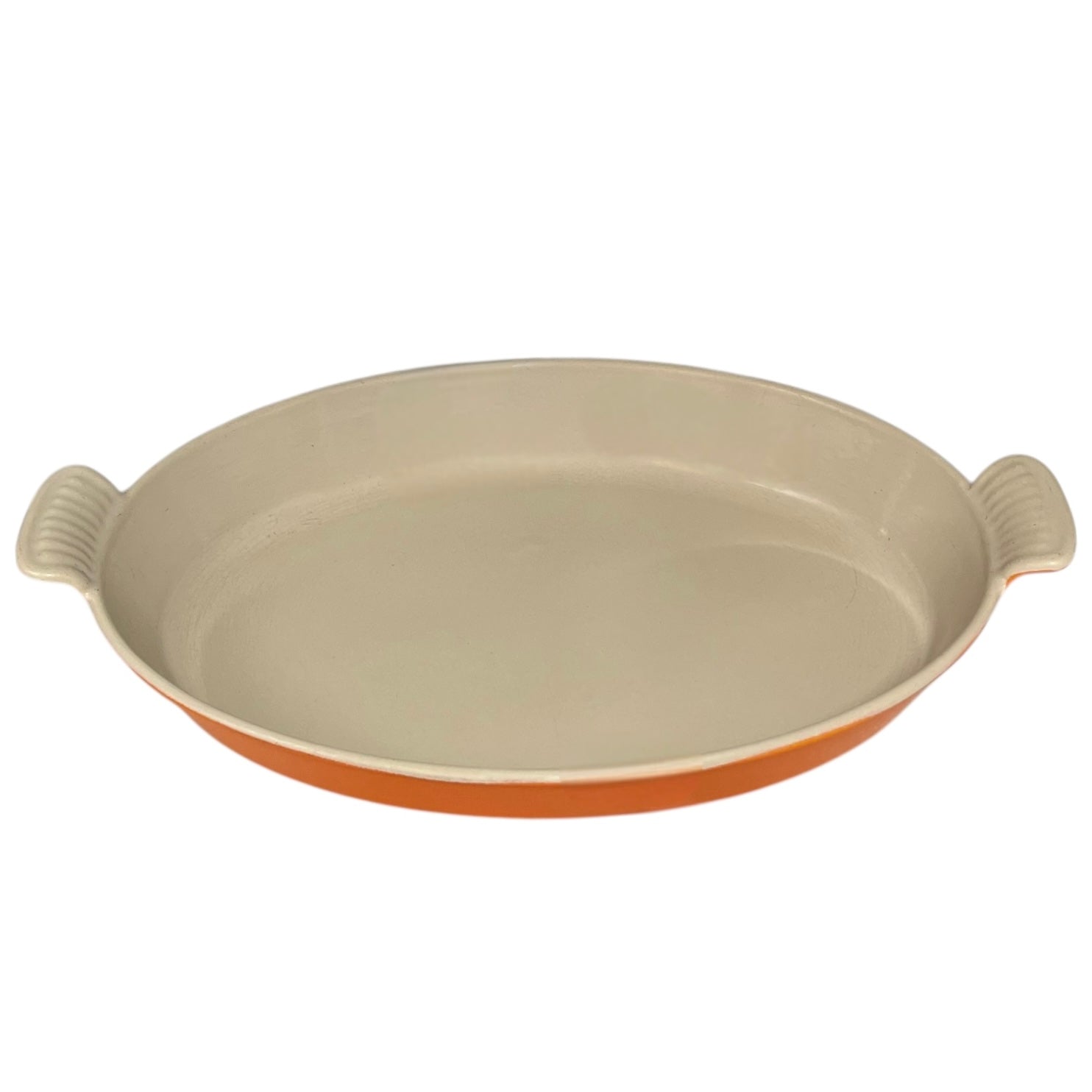French orange Le Creuset dish with beige interior on a white background