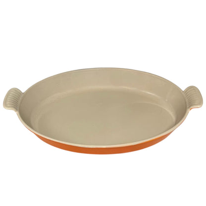French orange Le Creuset dish with beige interior on a white background
