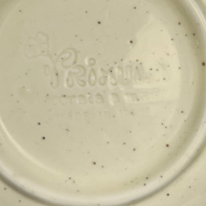 Close-up of a ceramic plate with speckled pattern and 'Primula' branding.