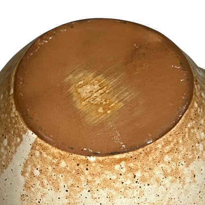 Close-up of a ceramic jug base with a brown glaze on a white background