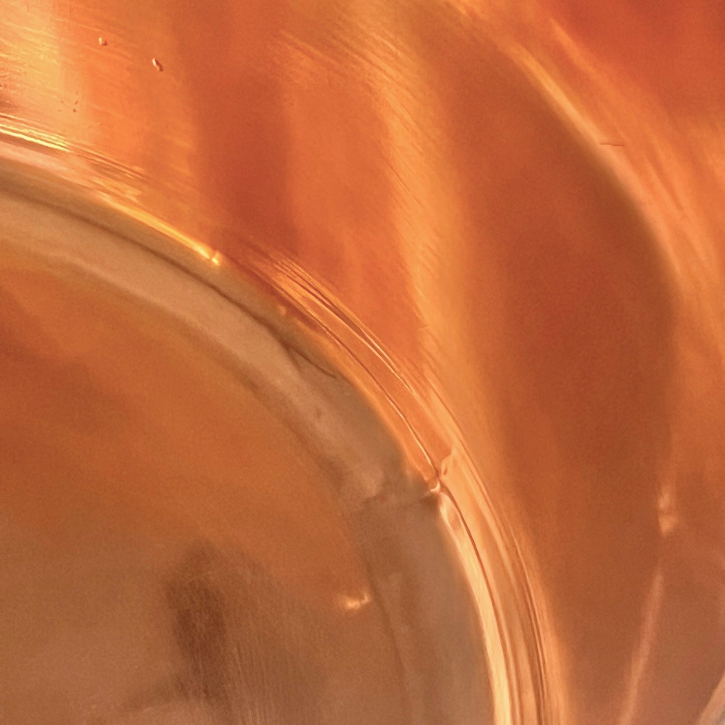 Close-up of a copper sink with a brass handle on a white background