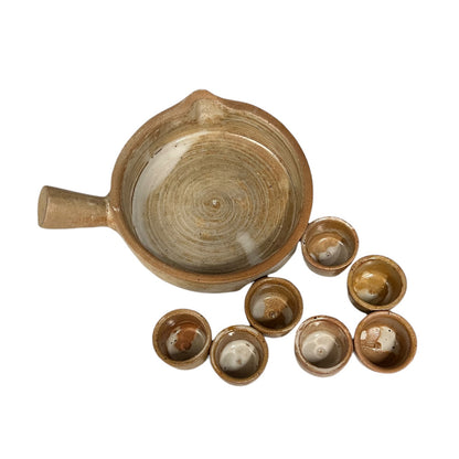 A rustic handmade ceramic escargot set featuring a large round bowl with a handle and six small matching cups, displayed on a clean white background.