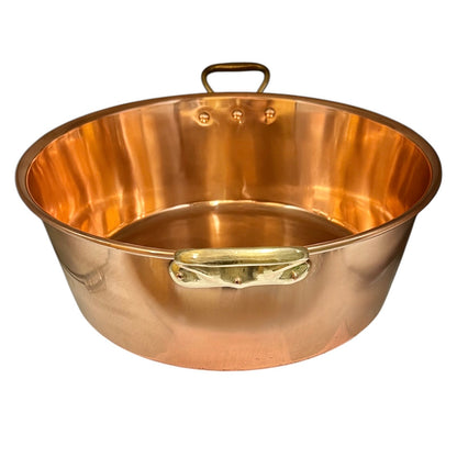 A large copper sink with a polished copper exterior, a polished brass side handle, and a darker brass top loop handle, shown on a solid white background.