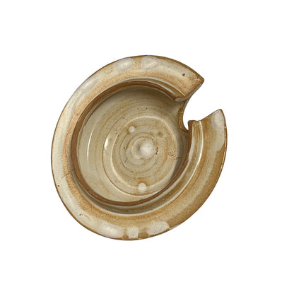 A handmade ceramic lid in earthy beige, brown, and cream tones, shown on a solid white background.