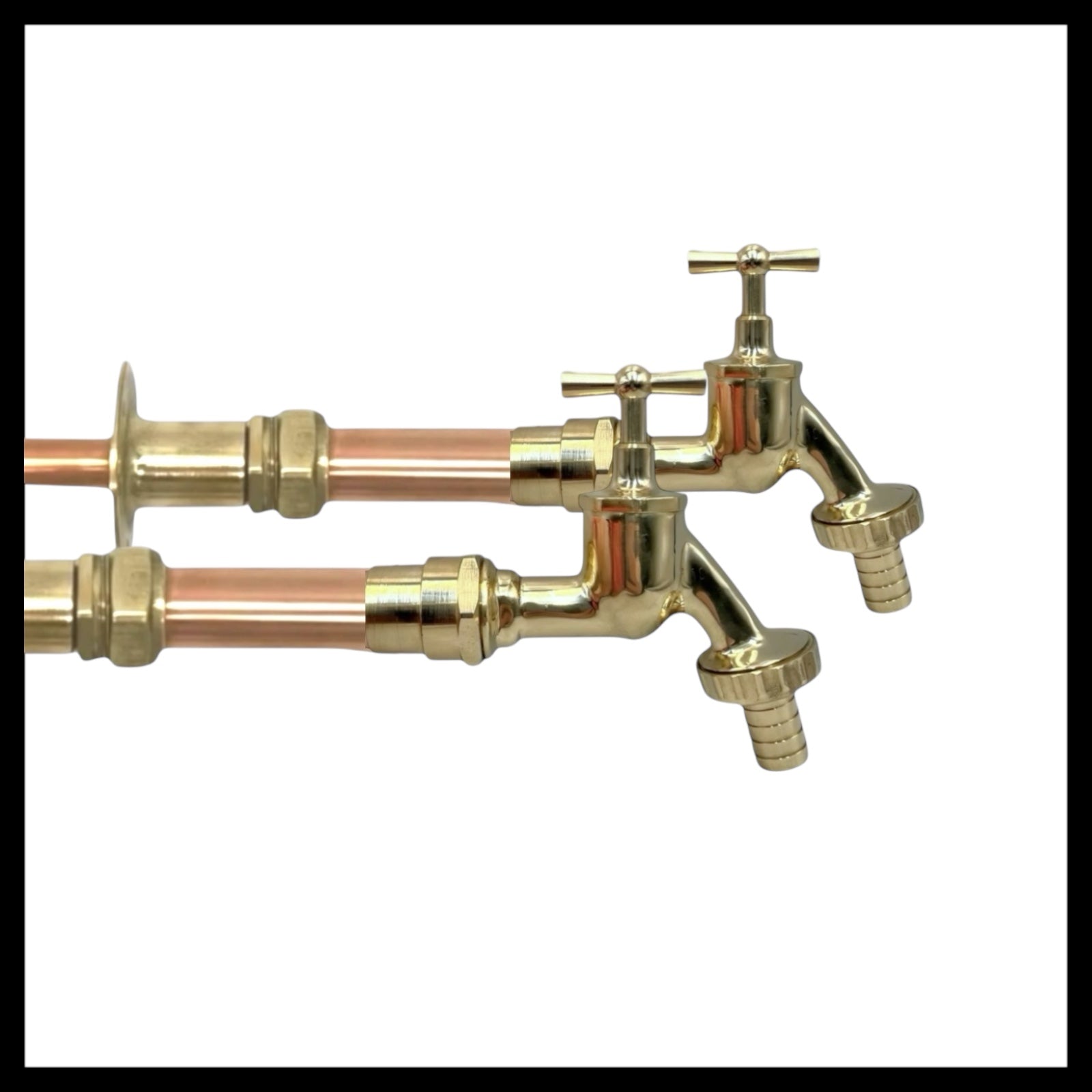 Pair of copper and brass wall taps with detachable nozzles on a white background