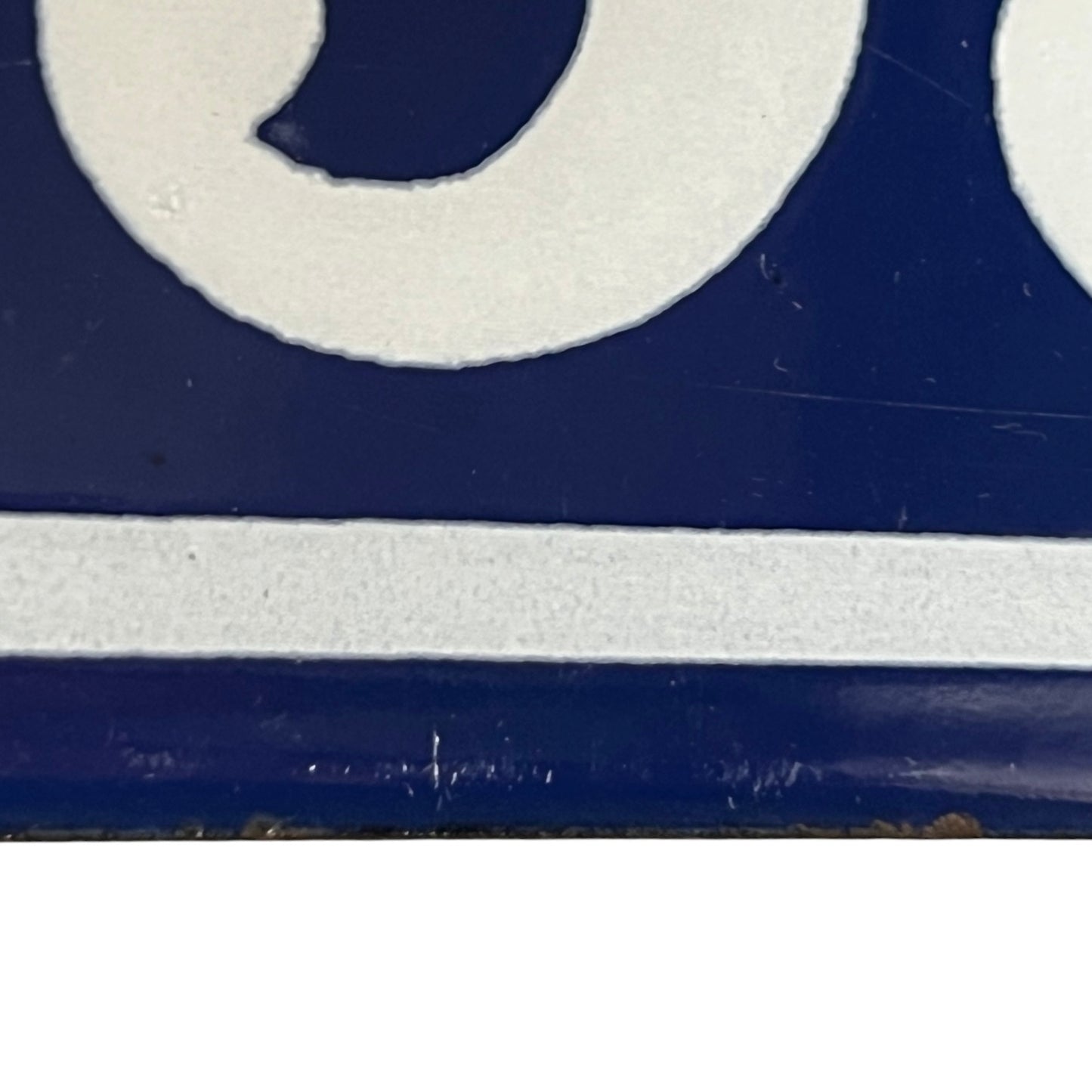 A close-up of a blue and white enamel-style surface with part of a white circular shape and a horizontal white stripe visible.