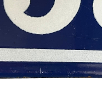A close-up of a blue and white enamel-style surface with part of a white circular shape and a horizontal white stripe visible.