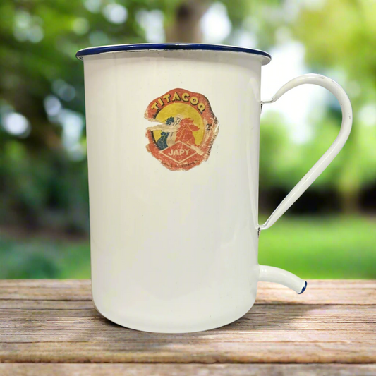 French vintage white and blue enamel planter or jug with a spout on a wooden table in a garden