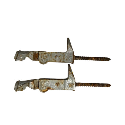 Two vintage metal shutter catches with rusted surfaces and threaded screw ends, shown on a plain white background.
