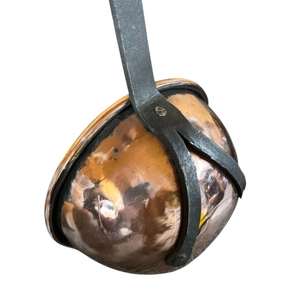 A vintage copper ladle with a dark metal strap and bracket, shown against a plain white background.
