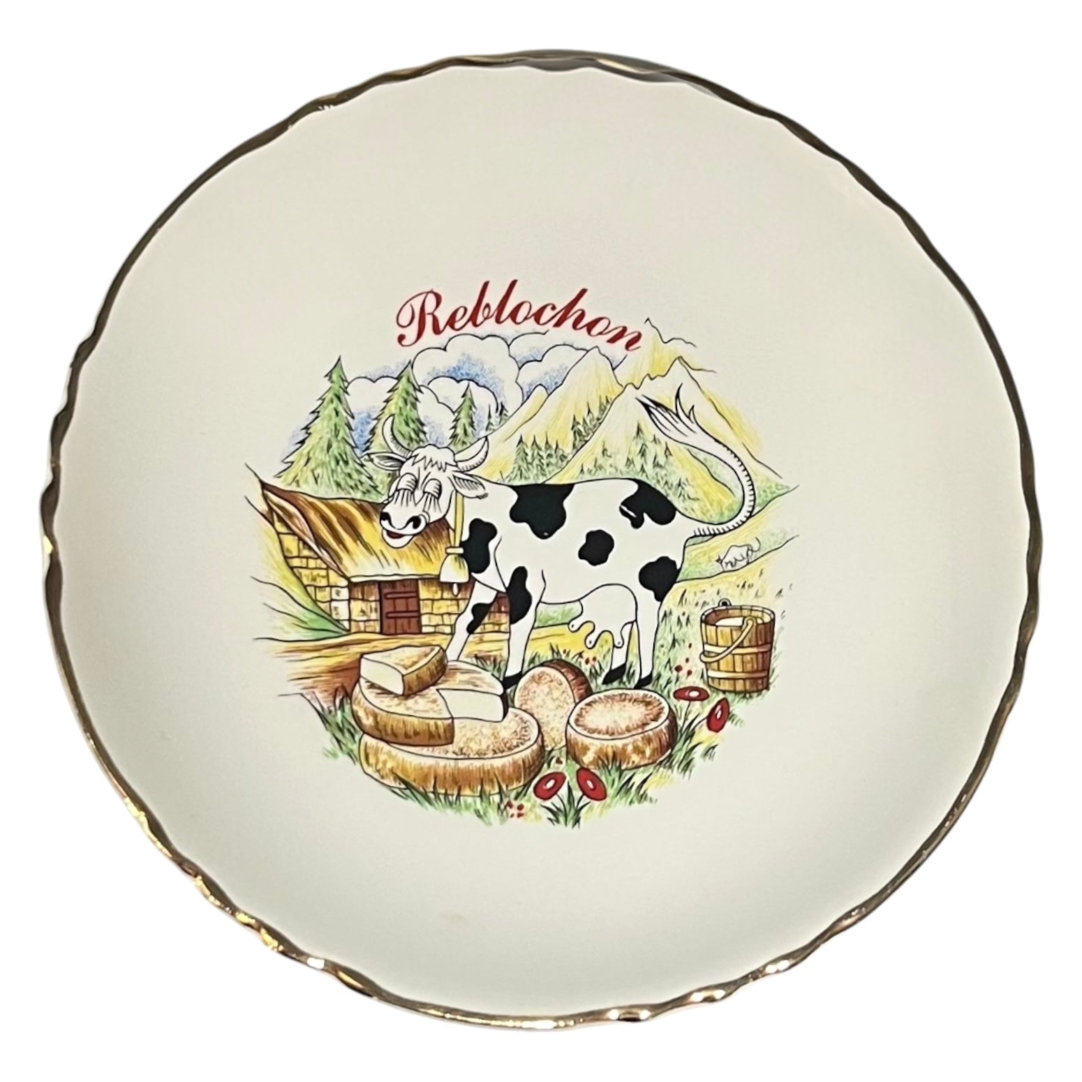 Decorative plate with a cow, cheese, and mountain landscape design on a white background.