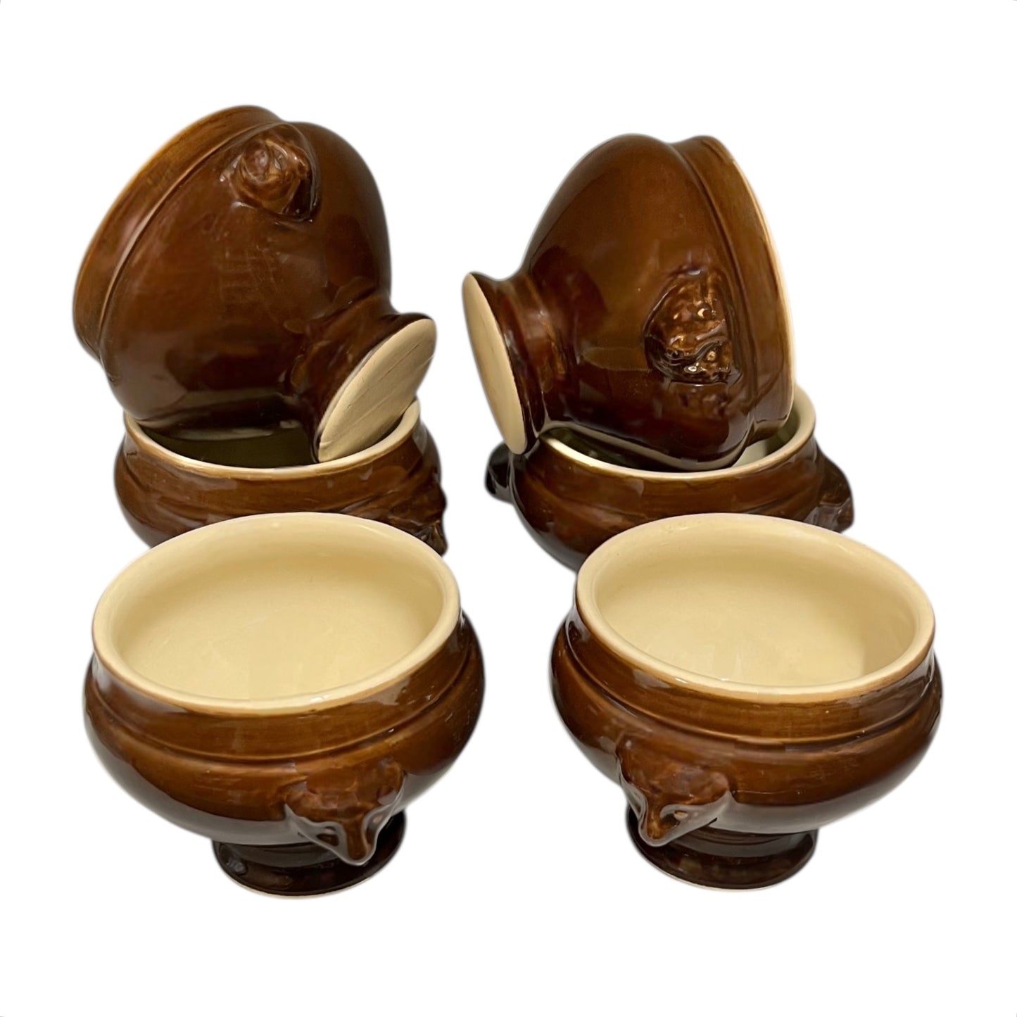 Set of six brown ceramic soup bowls with lion head handle designs on a white background