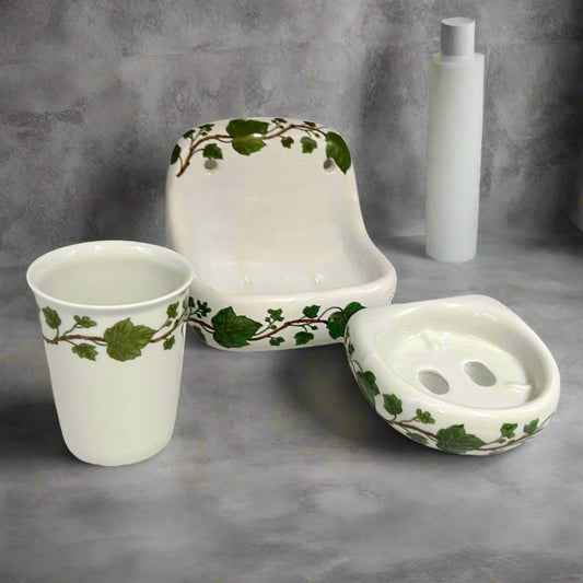 Porcelain bathroom accessory set with tumbler, toothbrush holder and soap dish featuring green leaf patterns on a white background