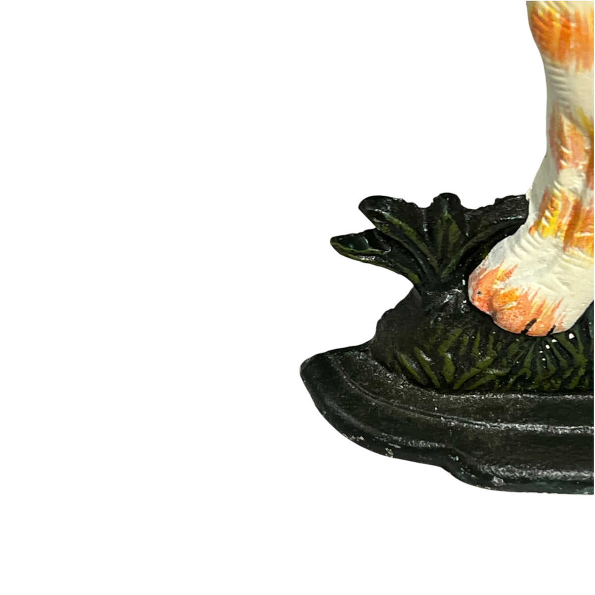 Close-up detail of a figurine's foot and lower body standing on a dark green leafy base against a white background.