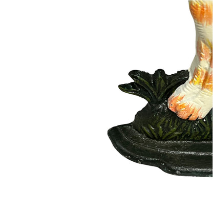 Close-up detail of a figurine's foot and lower body standing on a dark green leafy base against a white background.