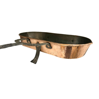 Antique French copper roasting pan with a long handle on a white background