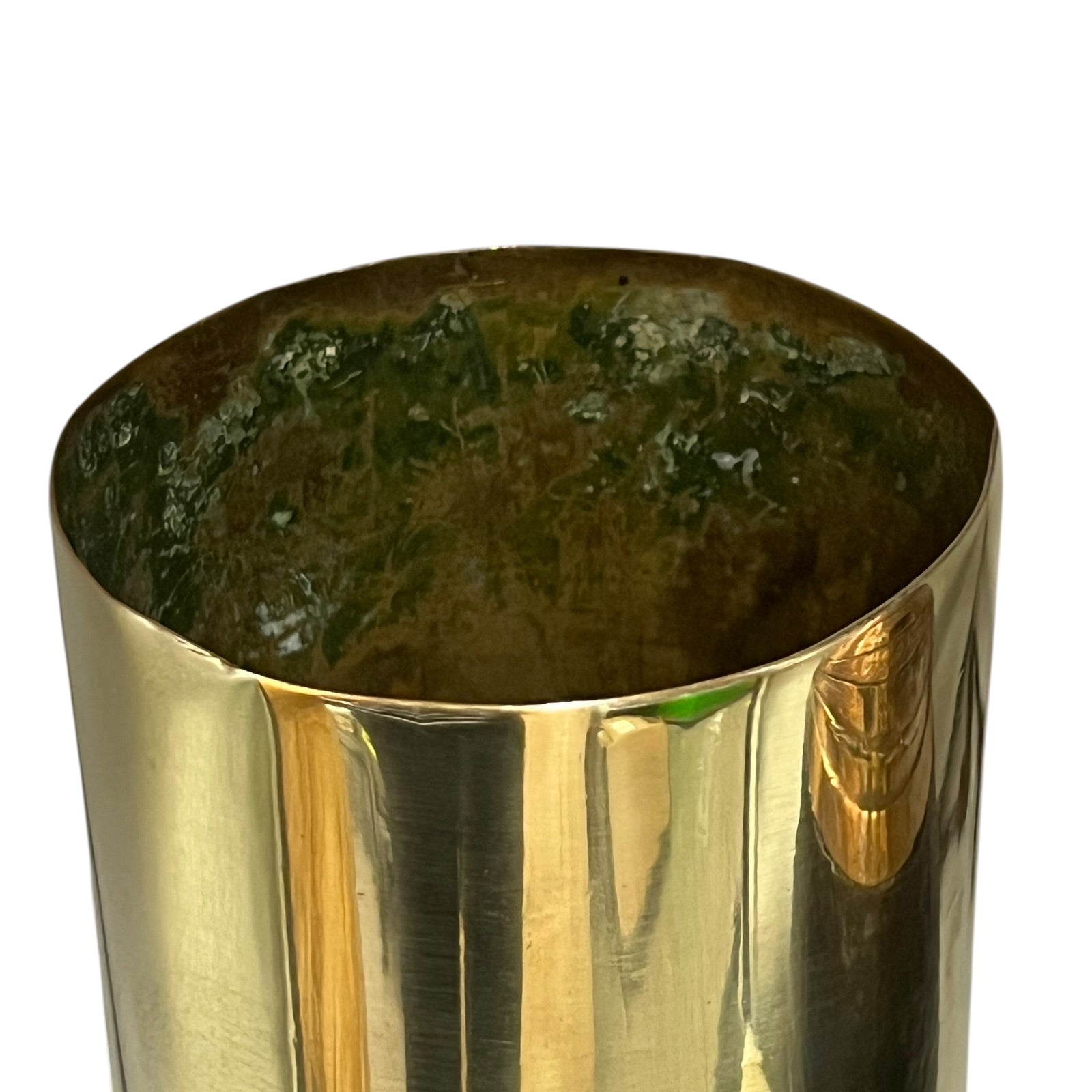 A close-up of a polished metallic cylindrical container or cup with a reflective gold exterior and a dark green textured interior, shown against a plain white background.