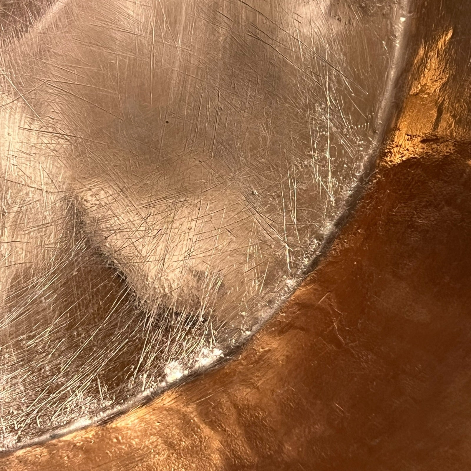 Close-up of a metal surface with scratches and a transition to a brownish color.