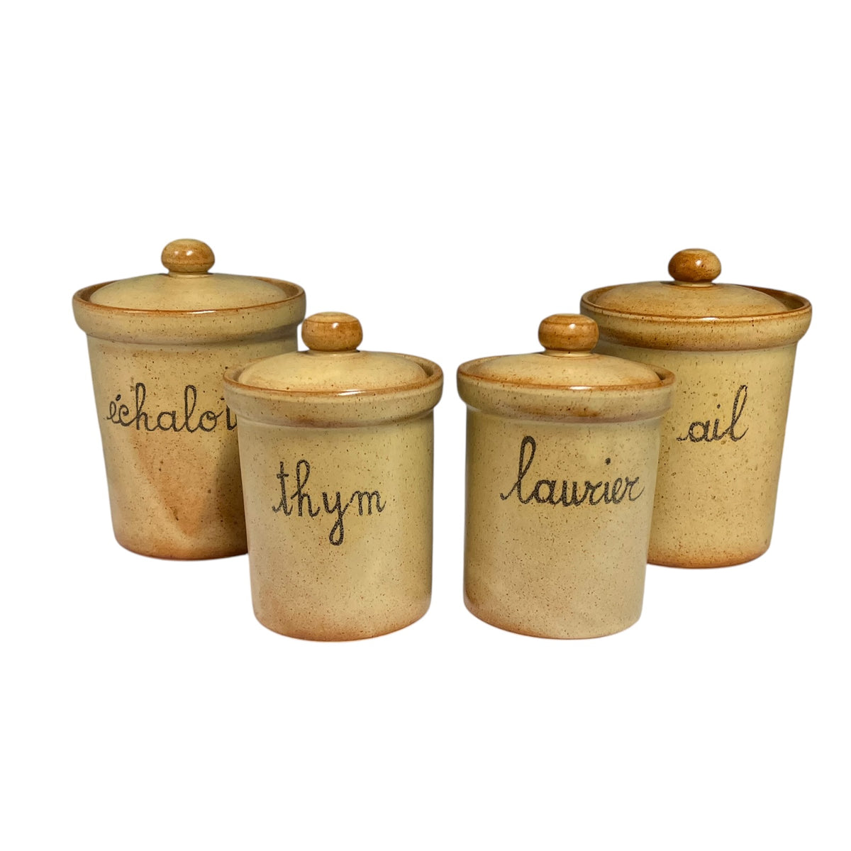 Set of four vintage French ceramic kitchen storage jars with matching lids, featuring warm beige speckled stoneware, brown glazed rims and handwritten French labels reading Échalote (shallot), Ail (garlic), Thym (thyme) and Laurier (bay leaf).