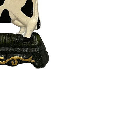 Close up of small cow shaped cast iron doorstop on a white background