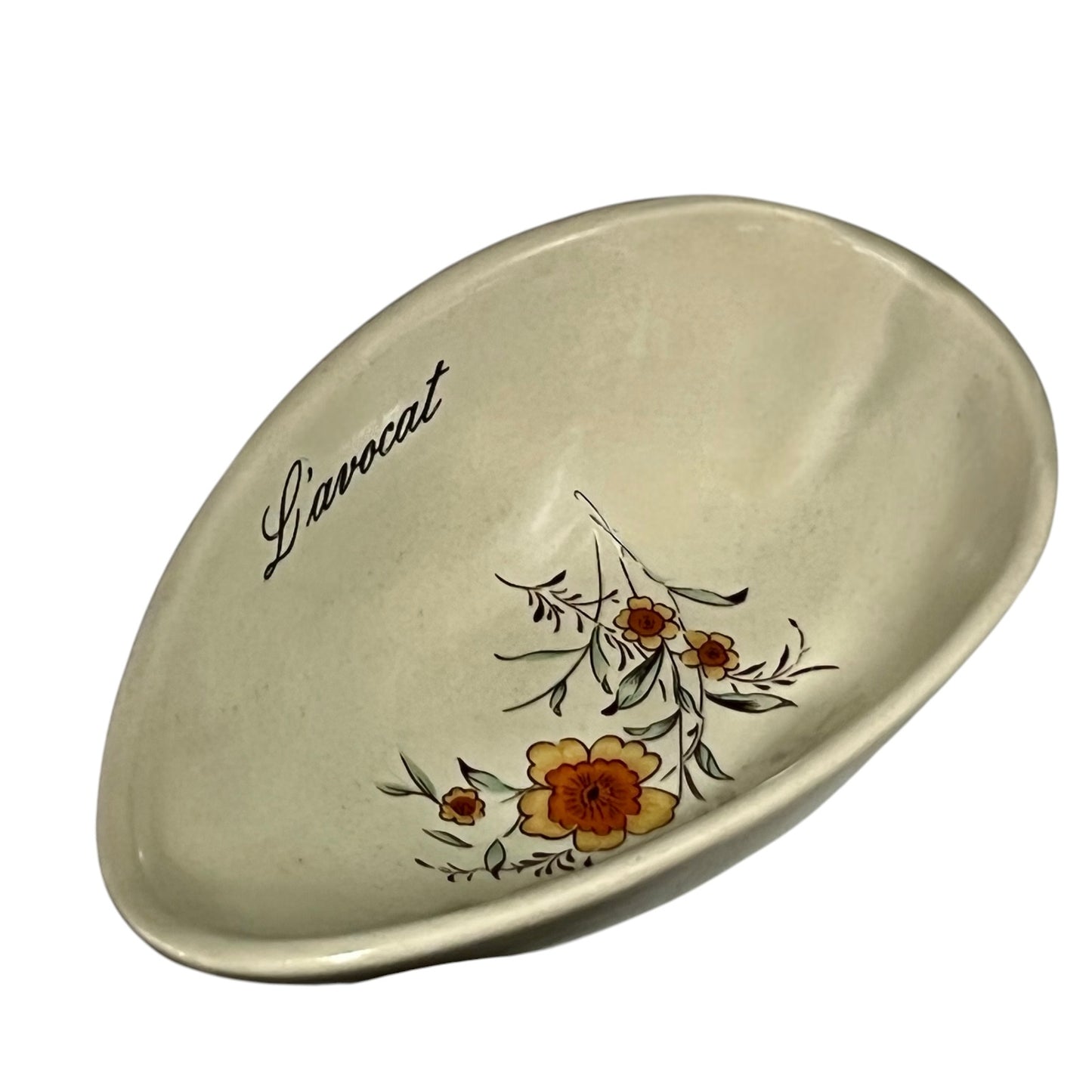 Beige ceramic dish with floral design and 'L'avocat' text on a white background