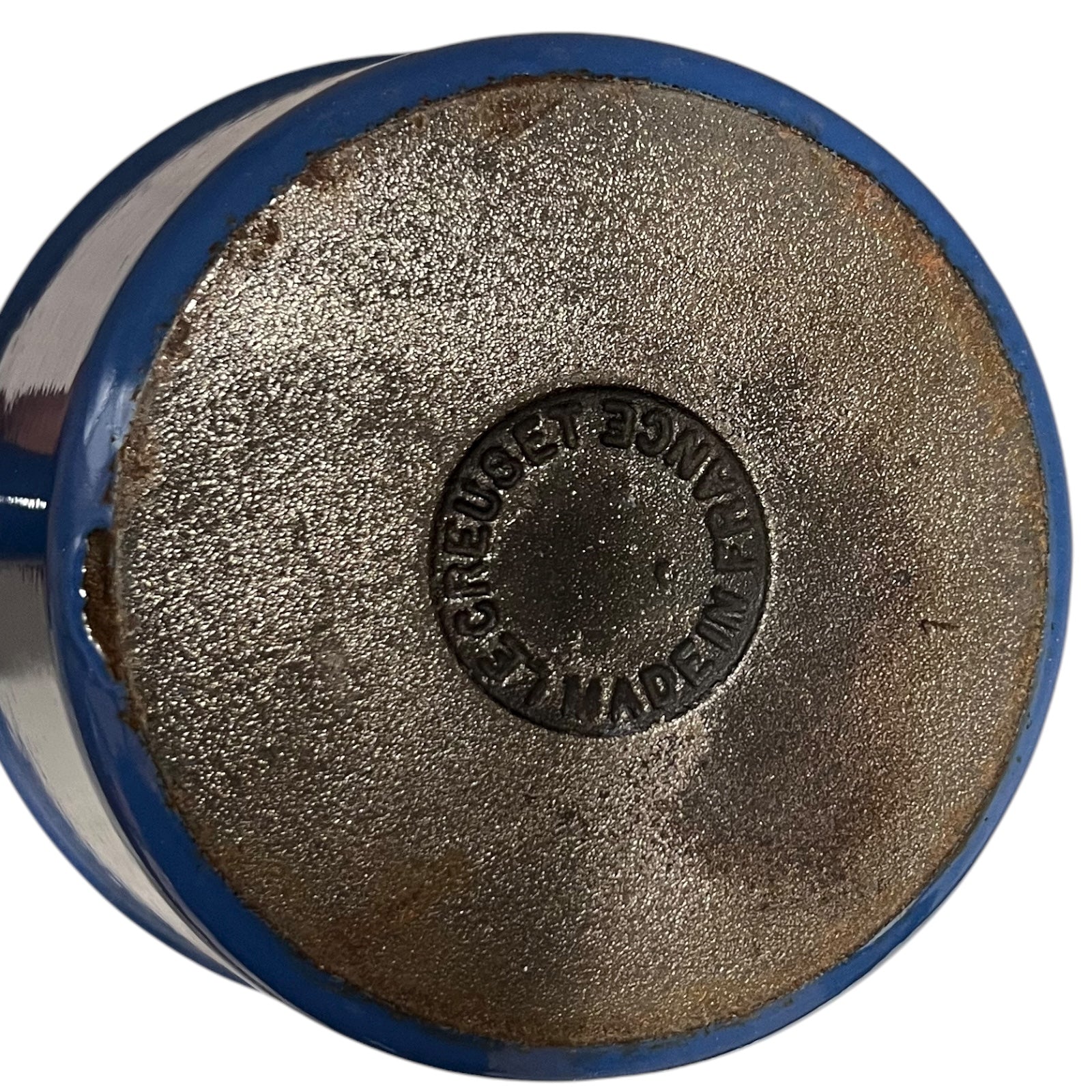 close up of blue cast iron pan with beige interior on a white background