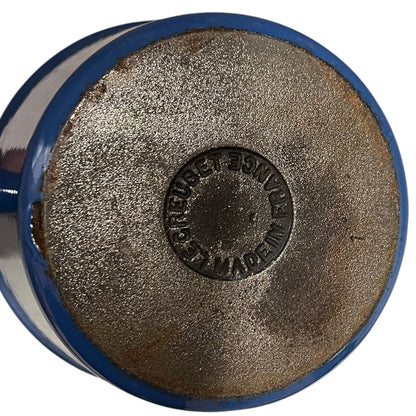 close up of blue cast iron pan with beige interior on a white background