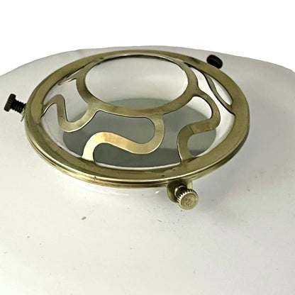 Close up of a white glass lamp shade with decorative design on a white background