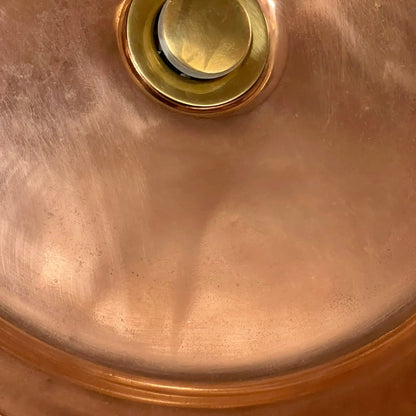 Close-up of a copper sink with a drain plug on a white background