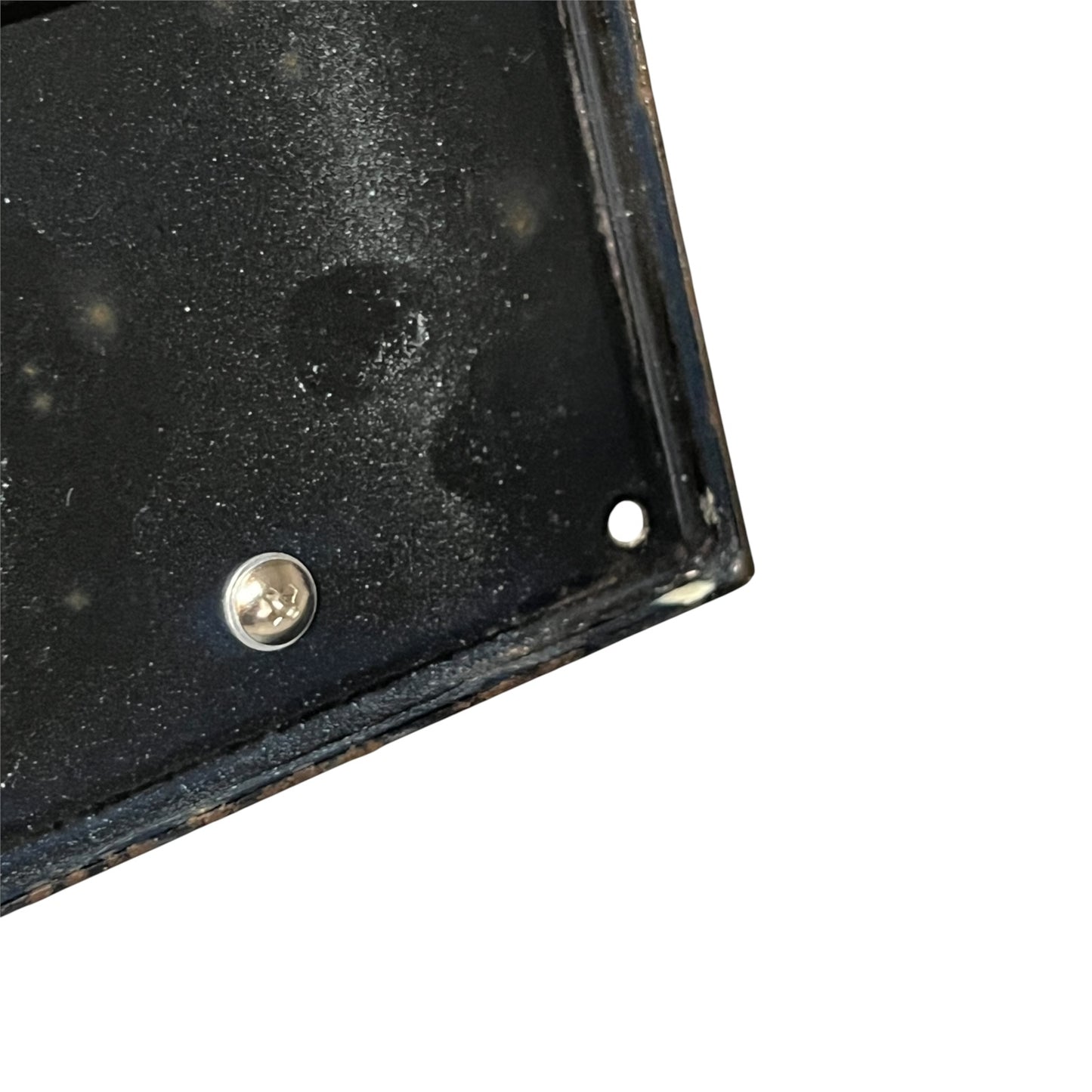 Close-up of the corner of a black metal mounting plate or bracket with a visible screw and mounting hole, shown against a plain white background.