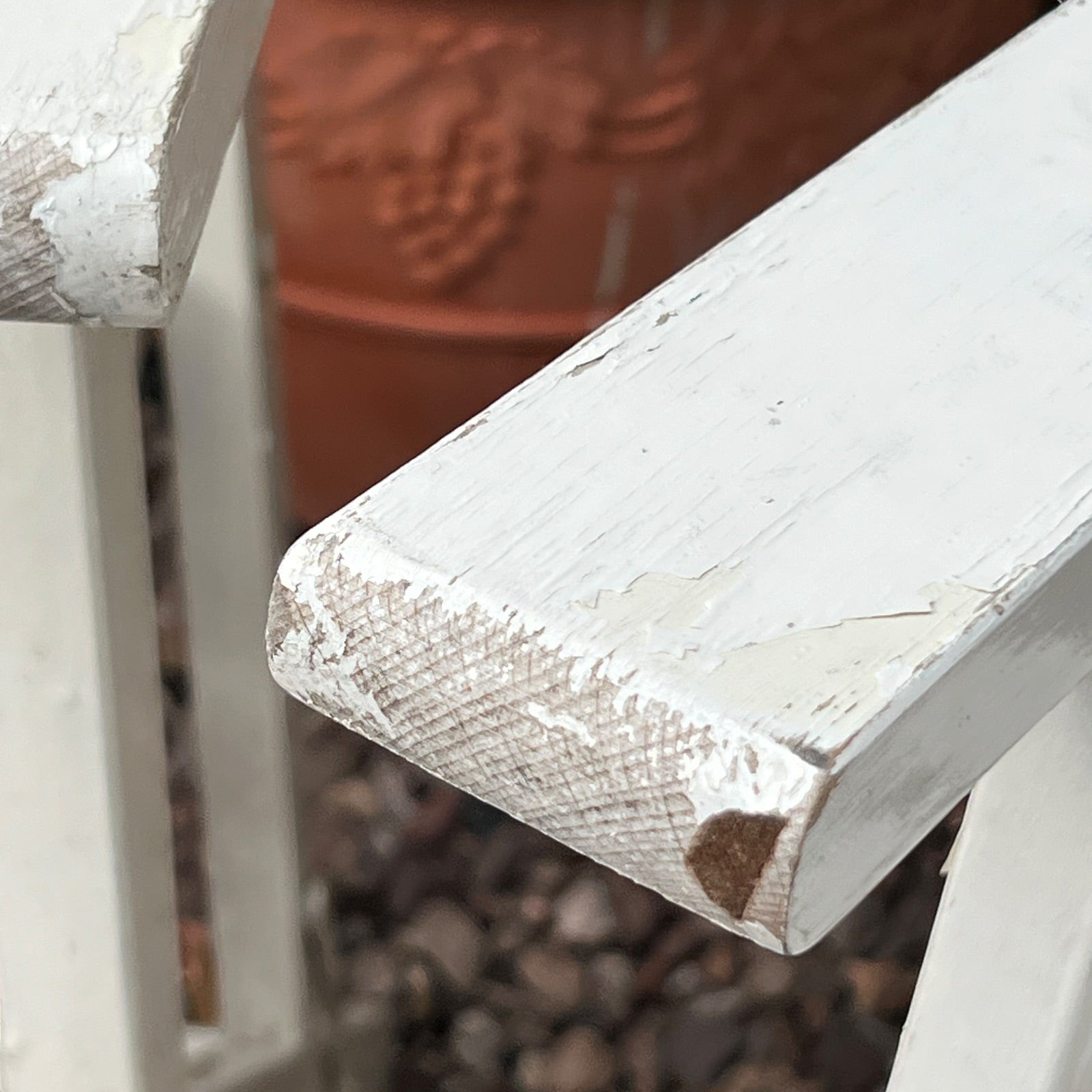 Close-up detail of French wooden slatted chairs, highlighting their condition in an outdoor setting.