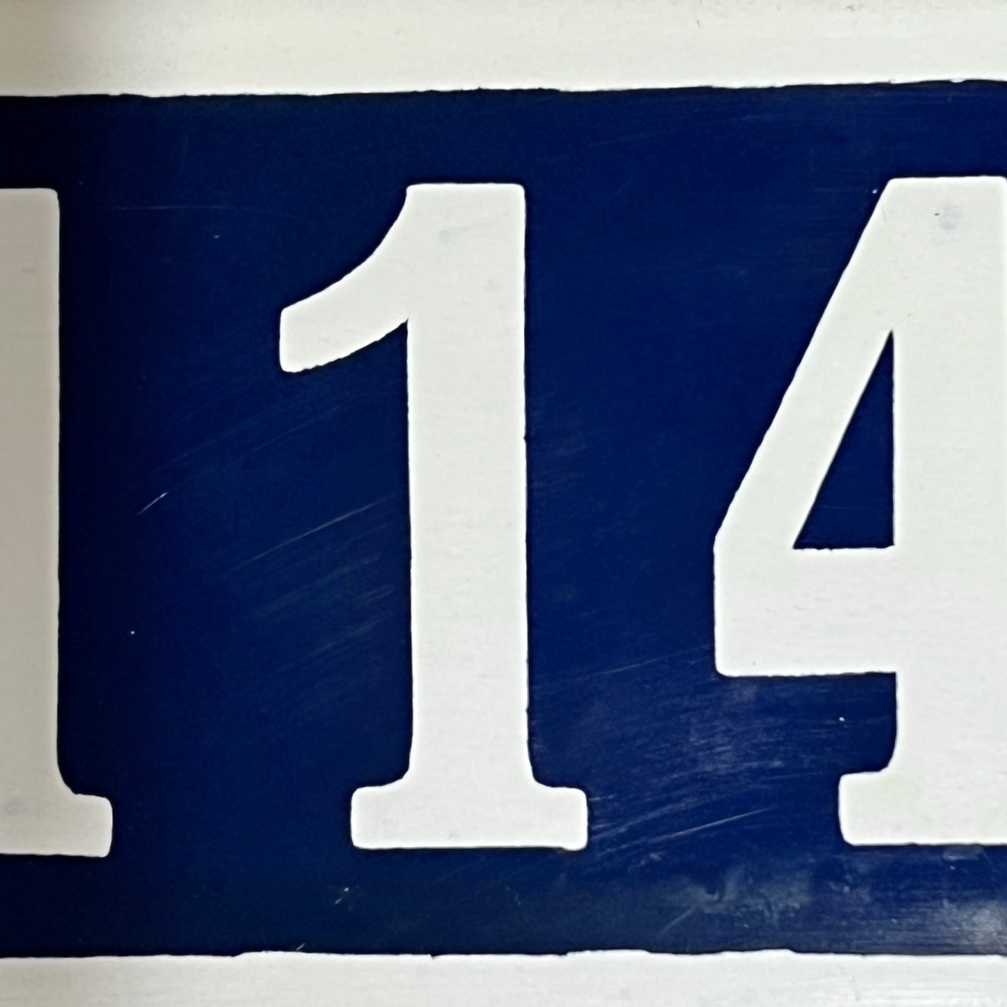 Close up of French enamel door number on a white background