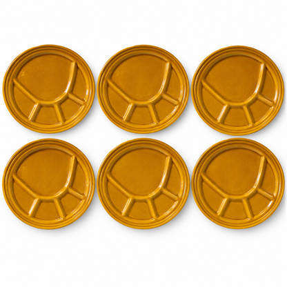 Six round mustard-yellow ceramic plates with a segmented, divided design, arranged in two rows of three on a white background.