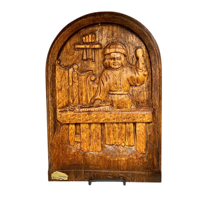 Wooden panel with carved scene of a person and objects on a white background