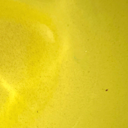 A close-up of a bright yellow textured surface with subtle tonal variation and tiny specks.