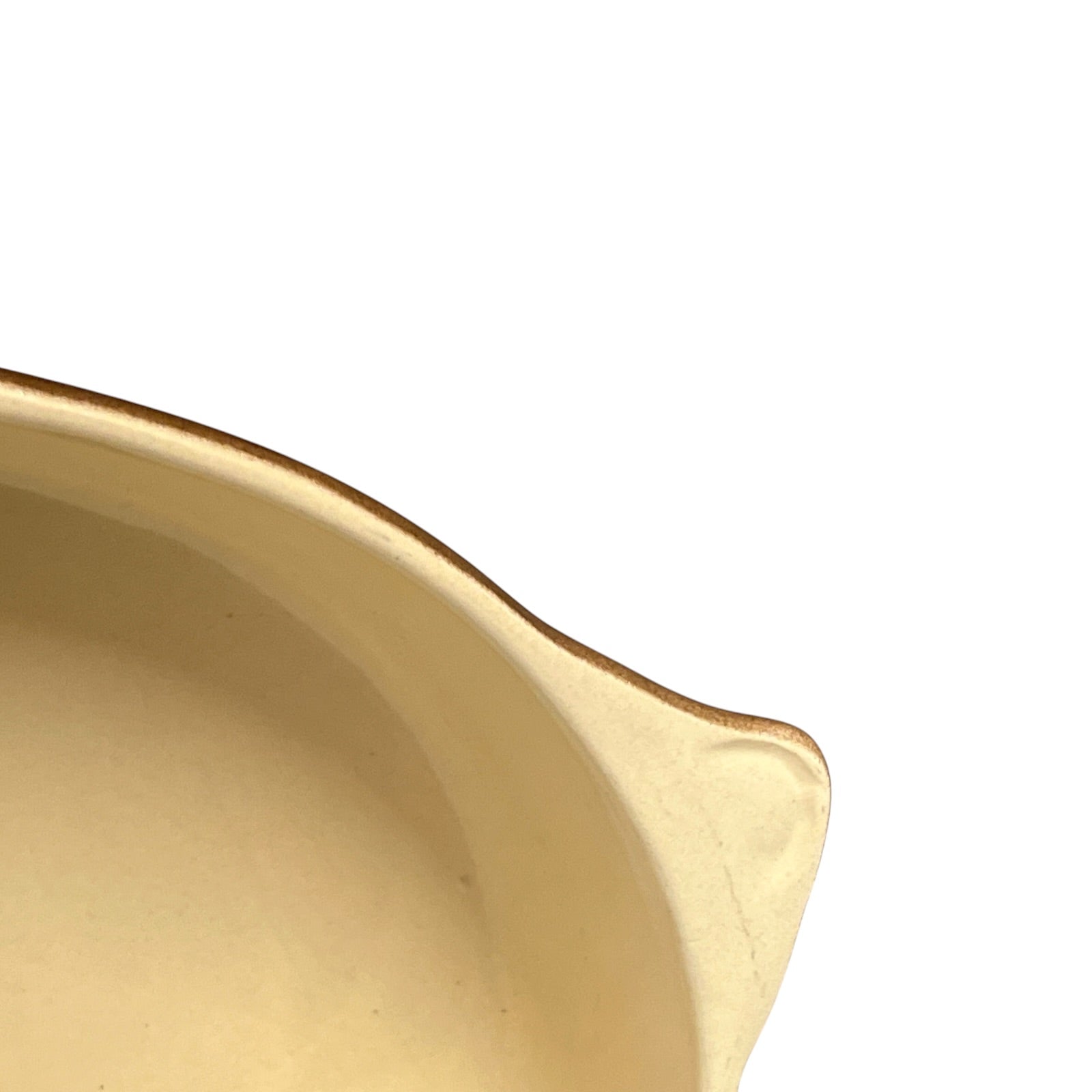 Close-up of a beige ceramic dish with a white background