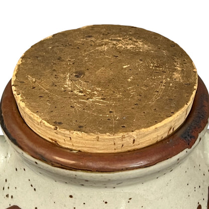 Close-up of a cork stopper on a ceramic container with a white background
