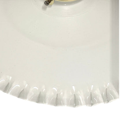 Close-up of a white glass lampshade with a scalloped edge.