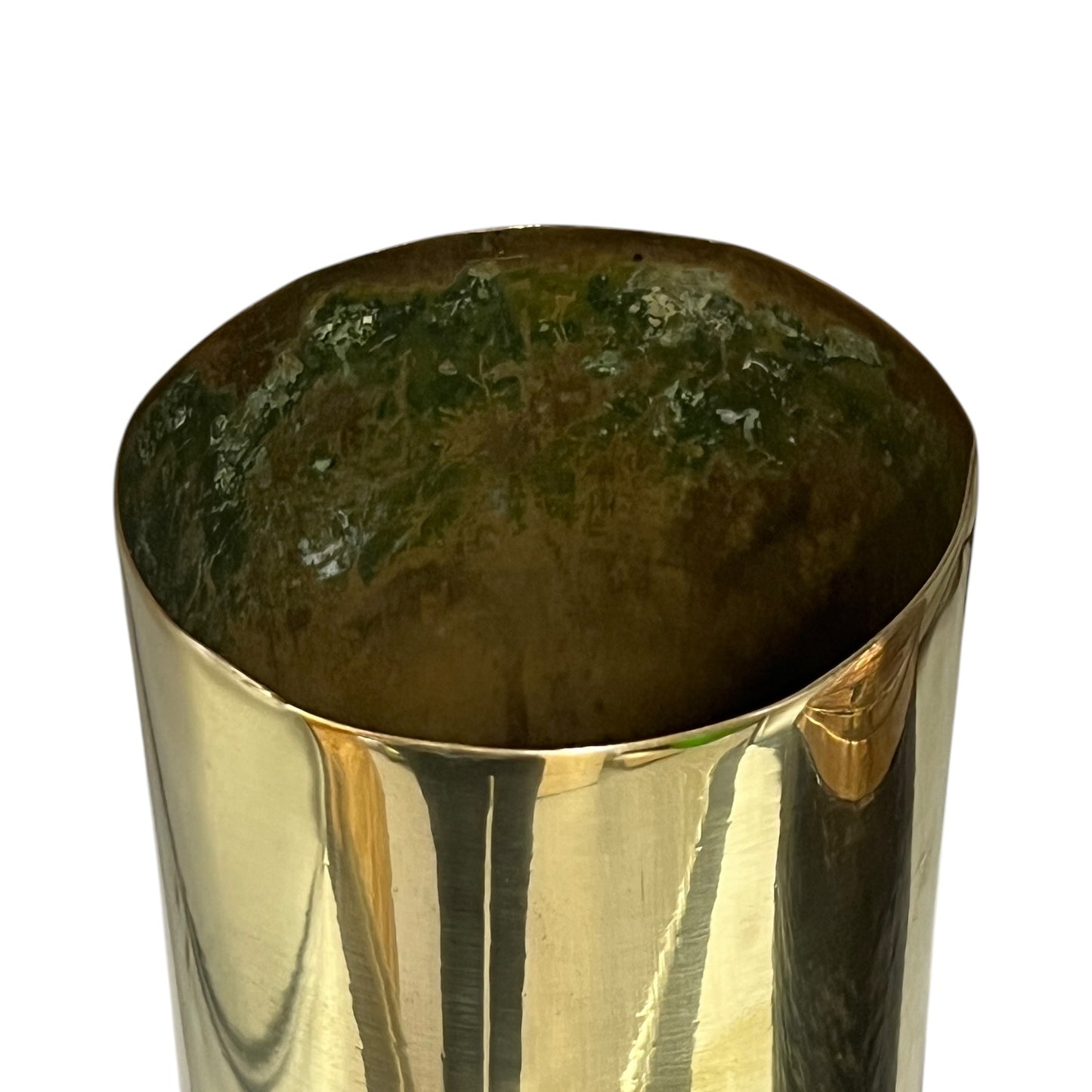 A close-up of a polished metallic cylindrical container, showing a reflective gold-toned exterior and a dark green-brown interior, set against a plain white background.